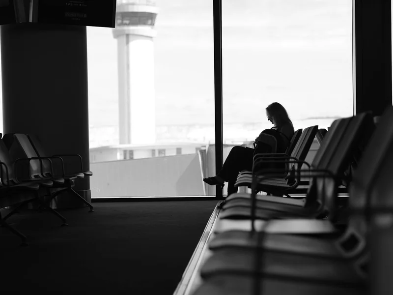 Viajeros con maletas de cabina en una sala de espera de aeropuerto